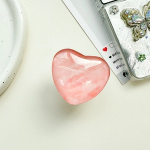 Detail eines herzförmigen rosa Kristall-Handyhalters mit glatter Marmortextur am Gehäuse