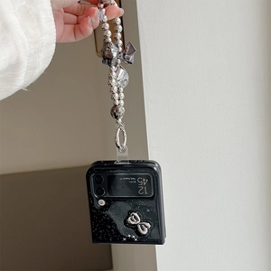 Dettaglio custodia Galaxy Z Flip nera glitterata con fiocco e catena di perle