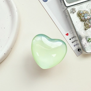 Nahaufnahme der herzförmigen Handyhalterung mit grünem Farbverlauf auf Ledertextur