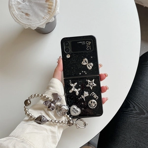 Dettaglio custodia Z Flip glitterata con ciondoli argento e cinturino di perline
