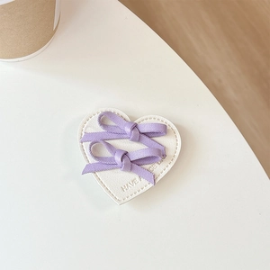 Détail de nœuds violets sur carte cœur en cuir blanc avec texte Have a Nice Day