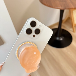 Orange Taiyaki phone grip with pearl detail on a white smartphone in a cozy setting