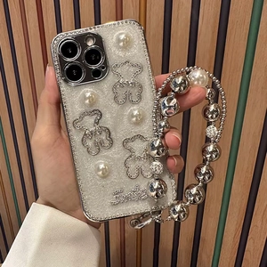 Detail of glitter iPhone case with pearl bear charms and a beaded wrist strap