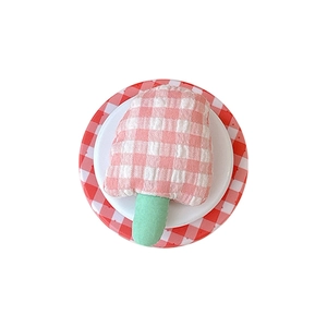 Plaid popsicle phone grip stand on a white ceramic plate with a red checkered base