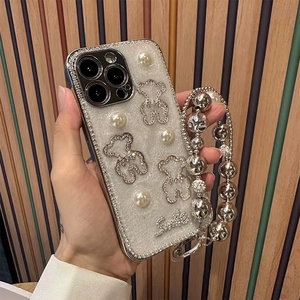 Detail of silver glitter phone case with pearl bear charms and a beaded hand strap
