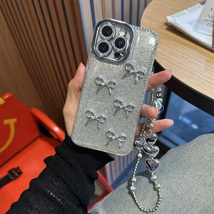 Close-up of silver glitter iPhone case with 3D bows and heart-shaped beaded wrist strap