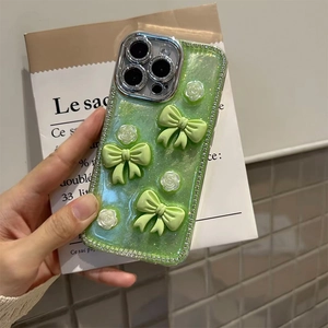 Close-up of glitter iPhone case with 3D green bows, white flowers and rhinestone edges