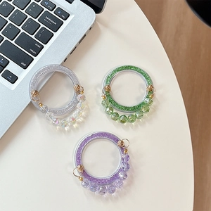 Close-up of glittered beaded rings with faceted charms in silver, green, and purple