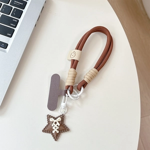 Detailed view of a brown braided phone lanyard with star pendant and smiley leather clasp