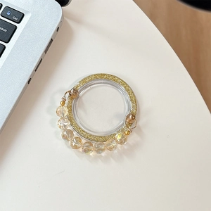 Detail of glitter phone ring holder featuring elegant champagne beads on white desk