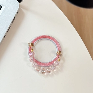 Pink glitter phone grip with clear faceted crystal bead chain on a white desktop