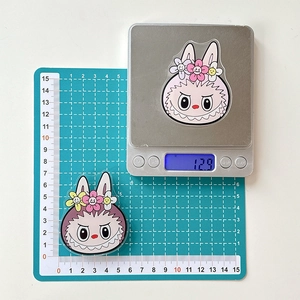 Detail shot of acrylic cartoon rabbit phone stand on scale showing 12.9g weight