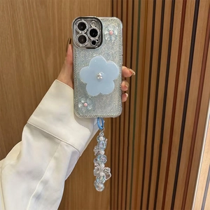 Close-up of glitter iPhone case with 3D floral pearl accents and blue beaded wrist strap