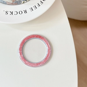 Macro detail of pink glitter magnetic phone grip base on a minimalist white desk