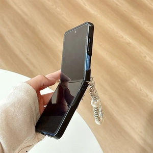 Detail of black folding phone case featuring a luxury pearl and silver chain handle