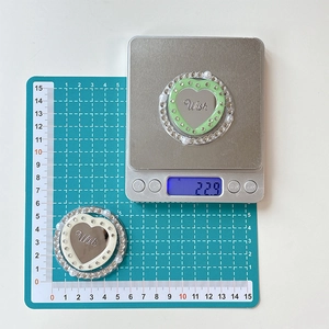 Macro detail showing heart-shaped rhinestones phone grip size and weight on scale