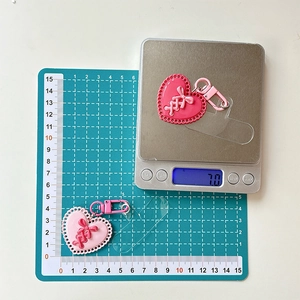 Gros plan de porte-clés cœur rose avec motifs en relief et boucle à ressort sur une balance