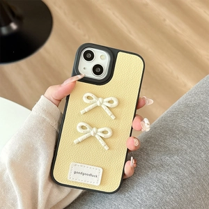 Detail of yellow lychee leather iPhone case featuring creamy white 3D bowknots with pink dots