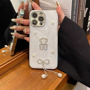 Close-up of glitter iPhone case featuring silver bear, pearls, and a tassel pendant