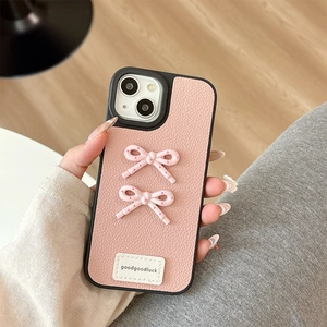 Detail of pink faux leather iPhone case with bow decoration and goodluck label