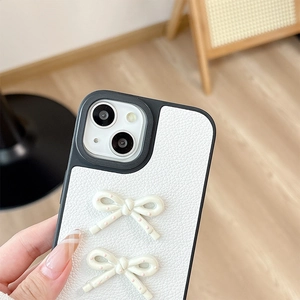 Close-up of white lychee leather phone case with 3D cream bows and pink polka dots