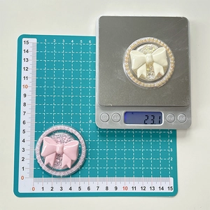 Macro view of cream and pink bow phone holders with pearl edges on a scale, 5cm diameter