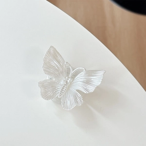 Detailed close-up of 3D white butterfly phone grip with fine radial texture and glitter