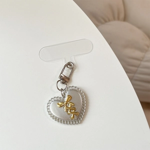 Détail du porte-clés coeur argenté avec noeud doré et patch transparent pour téléphone
