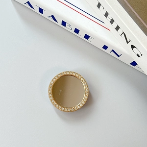 Close-up of a gold-plated phone grip with sparkling rhinestones and a reflective mirror