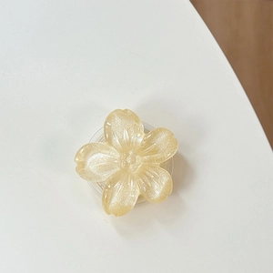Dettaglio di un supporto per telefono a fiore giallo pallido con petali glitterati