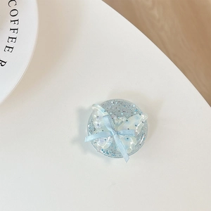 Detail of light blue sequin phone grip with 3D butterfly and ribbon bow on white desk