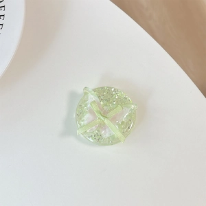 Detail of green resin phone grip with glitter, pink butterfly and bow ribbon accessory