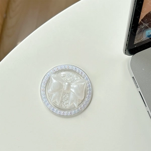 Close-up of pearl magnetic bow phone grip on desk showing delicate texture and elegant design