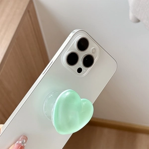 Detail of mint green heart-shaped glitter phone grip stand on a white smartphone