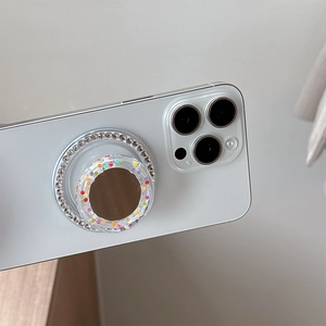 Close-up of a rhinestones phone grip featuring a mirror and colorful dots on a white phone