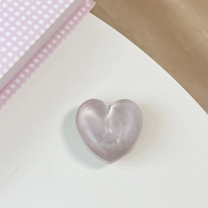 Detail of glitter heart phone socket with pearlescent purple gray finish on white surface