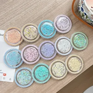 Glittery round phone grips with faux pearl edges in assorted pastel colors on wood