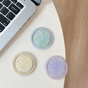 Close-up of glitter phone grips with pearl edges in light blue, yellow, and violet colors