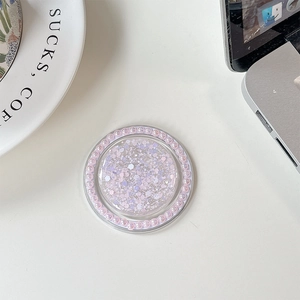 Close-up of a round phone grip featuring pink sequins and a pearl-beaded frame on desk