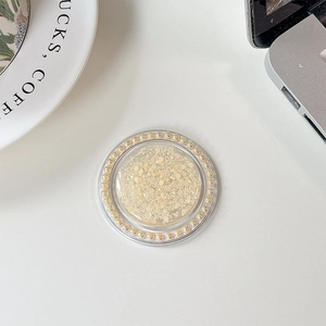 Close-up of a round phone grip featuring golden glitter and pearl embellishments