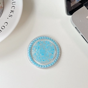 Macro detail of blue glitter phone grip with faux pearl border on a white desk