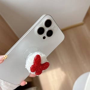 Macro shot of plush white base with sparkling red rhinestone butterfly on phone grip