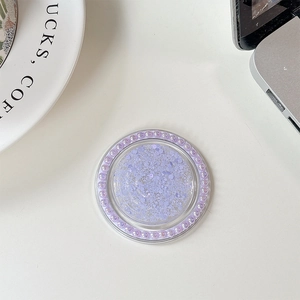 Macro shot of purple glitter phone grip stand with a ring of faux pearls on white desk