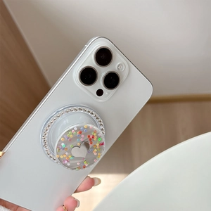 Close-up of a rhinestone phone grip with colorful sequins and a silver heart on a white case