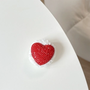 Detail of red rhinestone heart with white plush trim and luxury textured surface