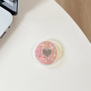 Macro shot of heart-shaped mirror phone grip with colorful polka dots on pink base