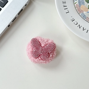 Detail of pink plush phone grip featuring a sparkling rhinestone butterfly pattern
