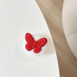 Macro shot of red rhinestone butterfly hair clip with white plush knitted base