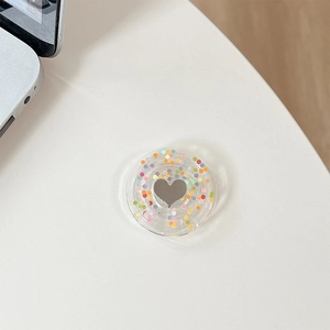Detail of a round resin phone socket with colorful sequins and a heart-shaped mirror