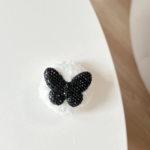 Detail of a black rhinestone butterfly charm with white faux fur plush round base